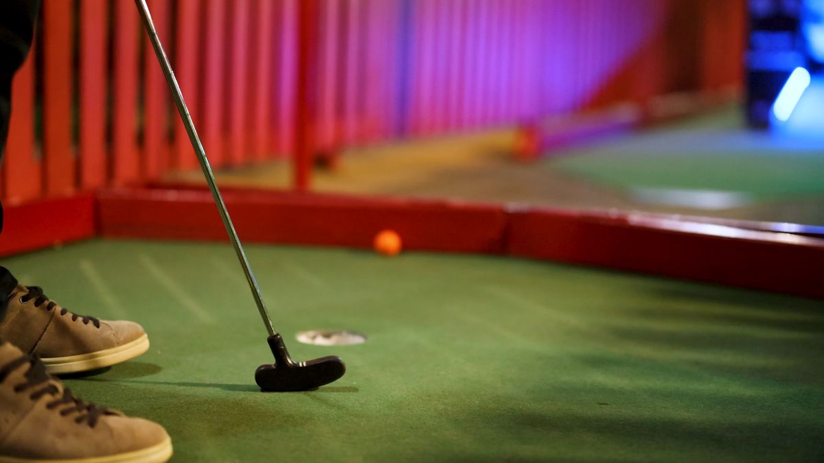 Indoor mini golf course with putting green and colorful lighting in Boston