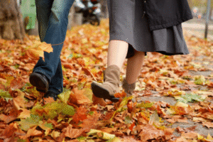 People walking in autumn leaves, dressed in fall attire