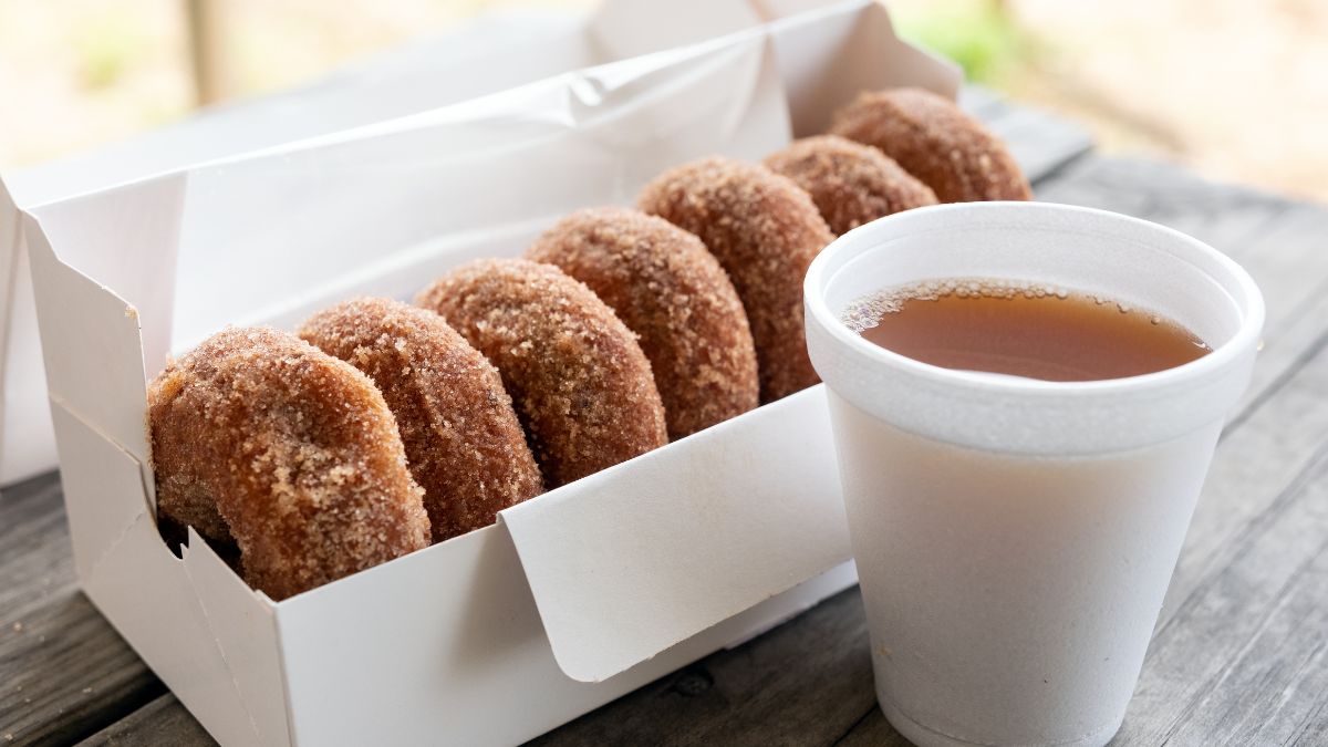 Box of apple cider donuts served with a cup of cider