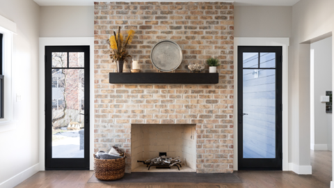 Clean fireplace in modern home with brick backdrop and decor