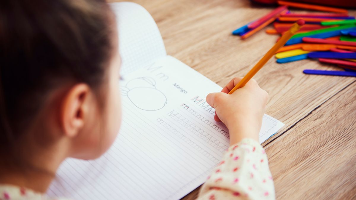 Girl working on a workbook with a pencil at a homework station