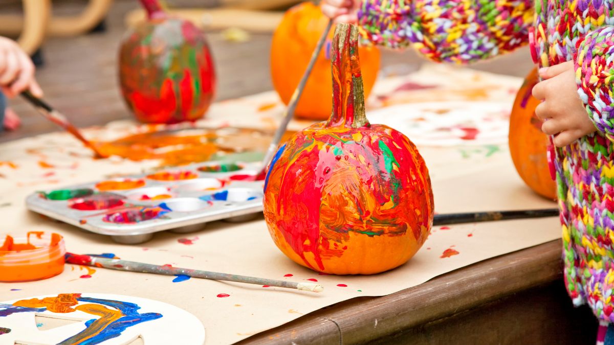 Children painting small pumpkins at a fall event in Wellesley, MA
