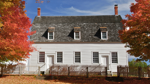 Old Home - Colonial New England home with bright fall foliage and leaves on the ground.