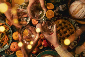 Image of people clinking their wine glasses over a classic Thanksgiving dinner.