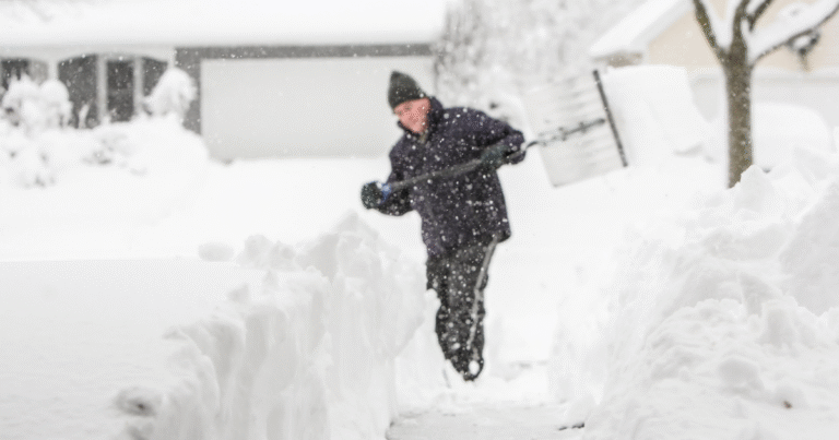 Person shoveling heavy snow after a large winter storm with a lot of snow