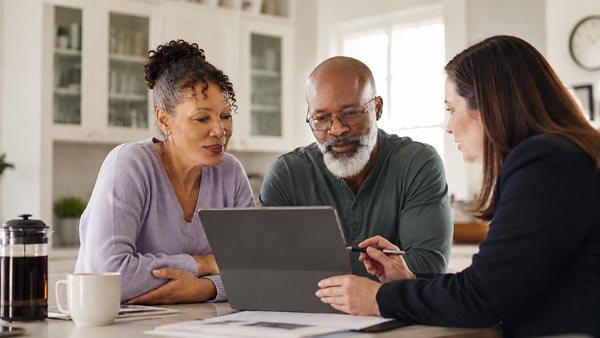 Real estate agent reviewing home search information with clients at a kitchen table