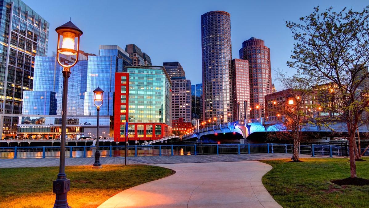Boston Harborwalk lit up and colorful at dusk.