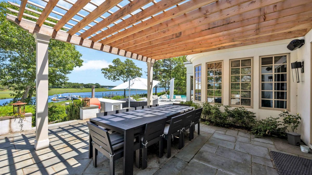 Covered waterfront patio with an outdoor dining area beside the pool